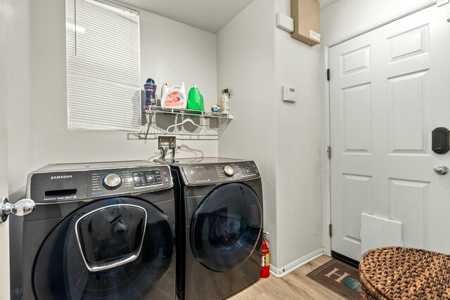 laundry room with washing machine and dryer and light hardwood / wood-style flooring