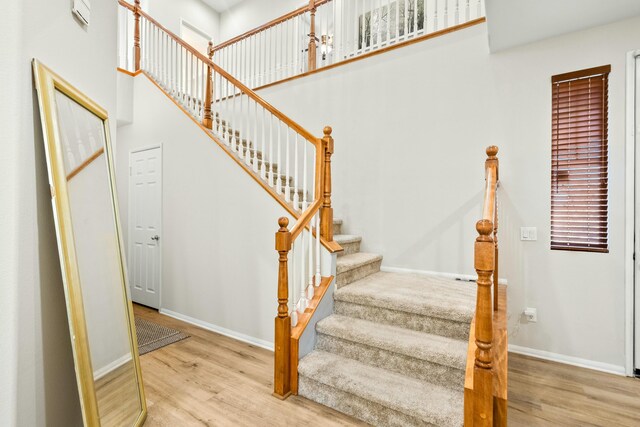 stairs featuring hardwood / wood-style floors and a towering ceiling