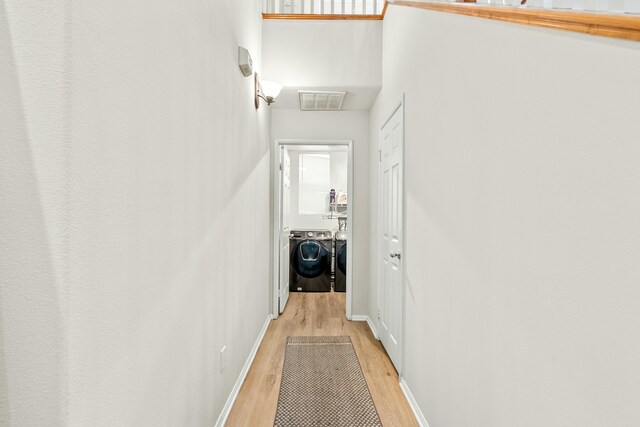 hall with washing machine and clothes dryer and light hardwood / wood-style flooring