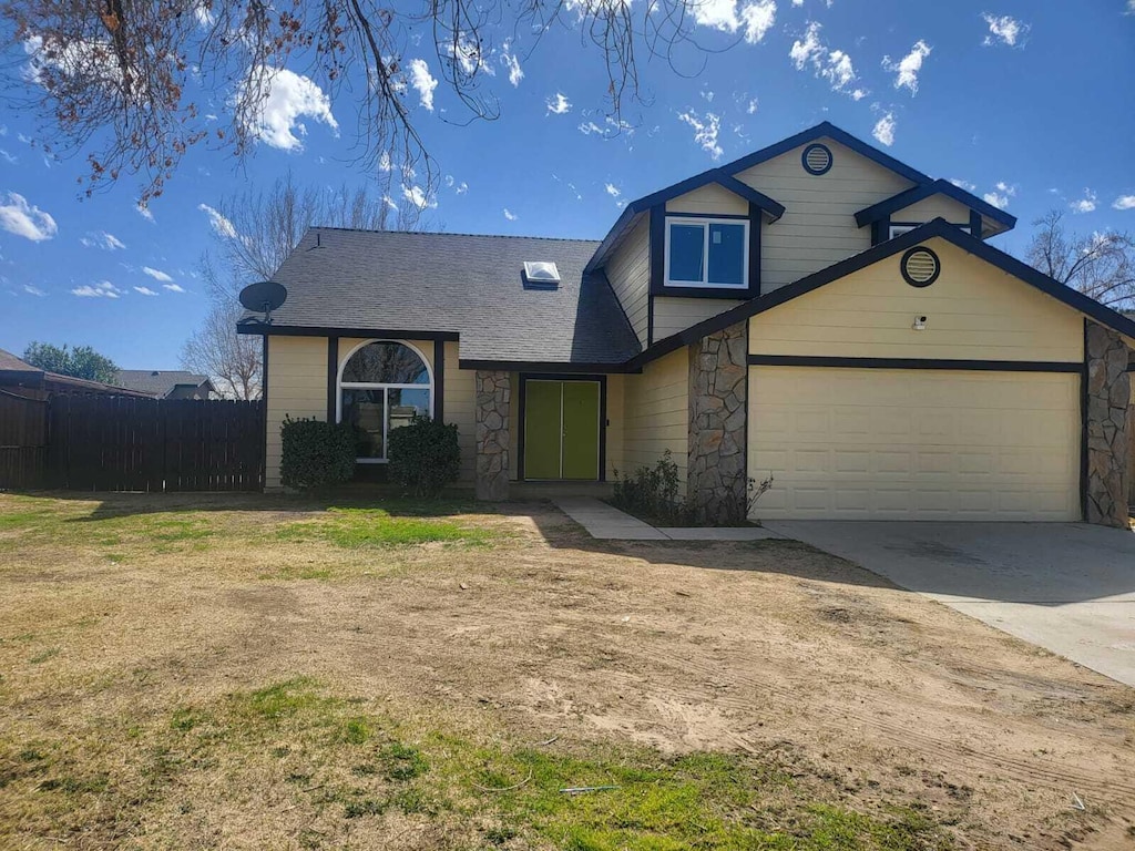 view of front of house with a garage, fence, stone siding, driveway, and a front yard