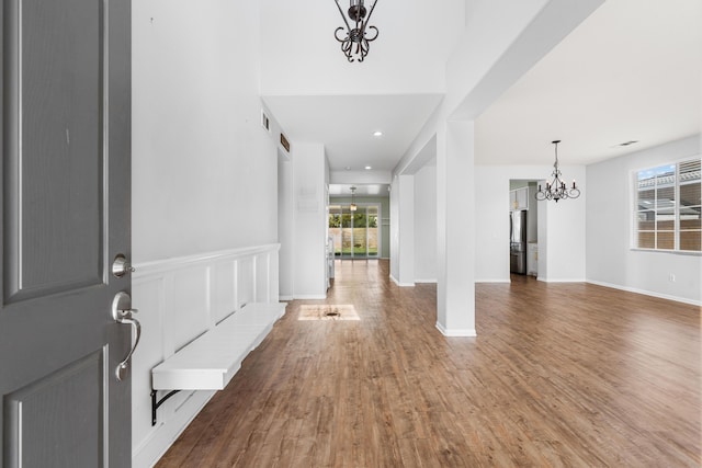 entrance foyer with an inviting chandelier, baseboards, visible vents, and wood finished floors