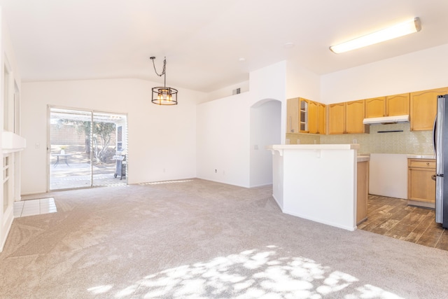 kitchen with vaulted ceiling, light colored carpet, stainless steel fridge, and decorative light fixtures