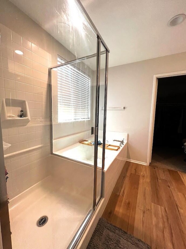 bathroom with hardwood / wood-style floors and shower with separate bathtub