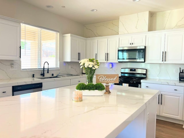 kitchen with light stone counters, sink, white cabinets, and stainless steel appliances