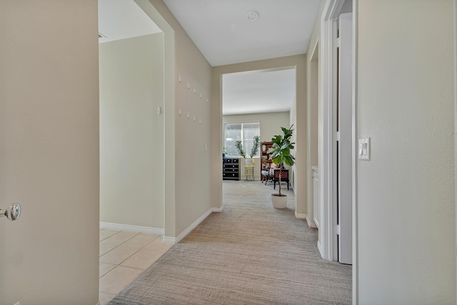 hallway featuring light tile patterned flooring and light colored carpet