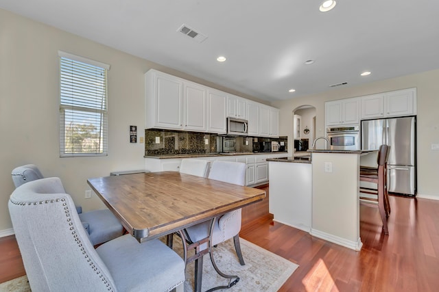 kitchen featuring dark wood finished floors, visible vents, arched walkways, dark countertops, and appliances with stainless steel finishes
