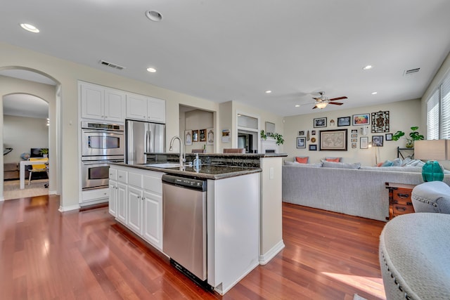 kitchen with a sink, stainless steel appliances, visible vents, ceiling fan, and arched walkways