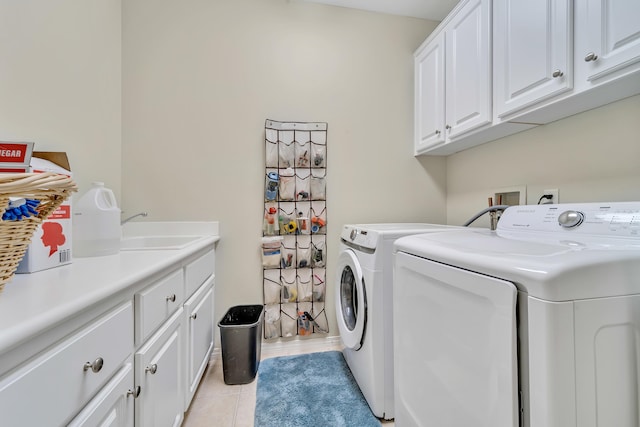 washroom with cabinet space, washing machine and dryer, light tile patterned floors, and a sink