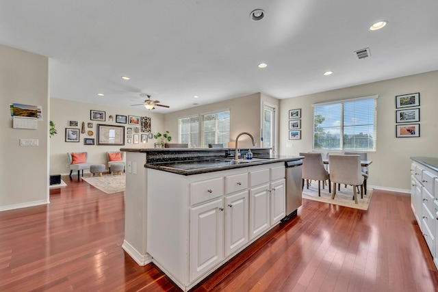 kitchen featuring stainless steel dishwasher, white cabinets, a sink, and dark wood-type flooring
