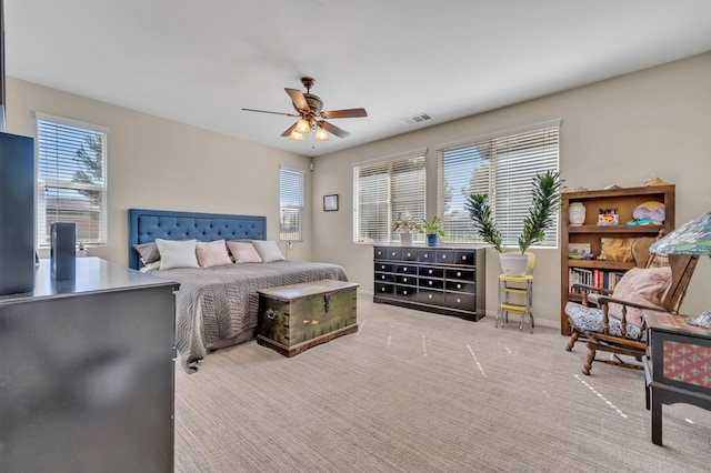 carpeted bedroom featuring multiple windows, visible vents, baseboards, and ceiling fan