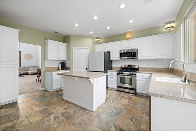 kitchen with visible vents, stone finish flooring, appliances with stainless steel finishes, white cabinets, and a sink