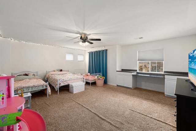 bedroom with visible vents, light carpet, ceiling fan, and built in study area