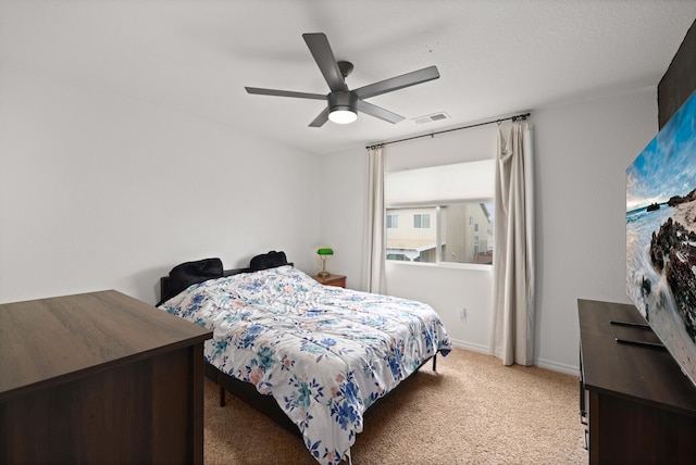 bedroom with visible vents, light colored carpet, baseboards, and a ceiling fan