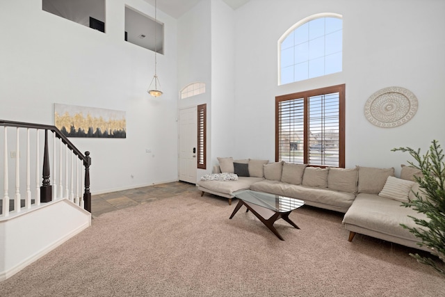 carpeted living room featuring baseboards and stairs