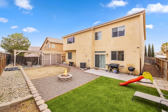 rear view of house with stucco siding, a pergola, a fenced backyard, a fire pit, and a patio area