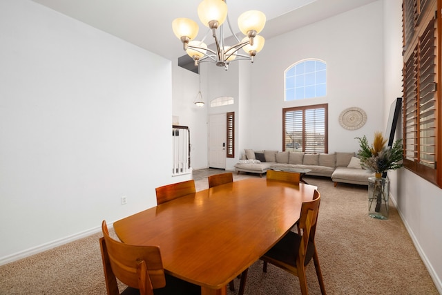 carpeted dining space featuring baseboards, a notable chandelier, and a towering ceiling