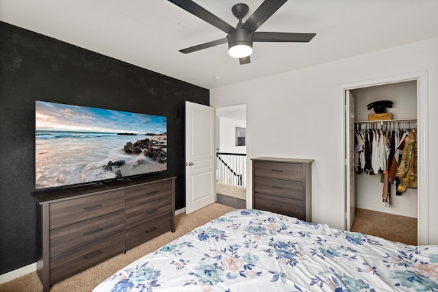 carpeted bedroom with a walk in closet, a ceiling fan, a closet, and baseboards