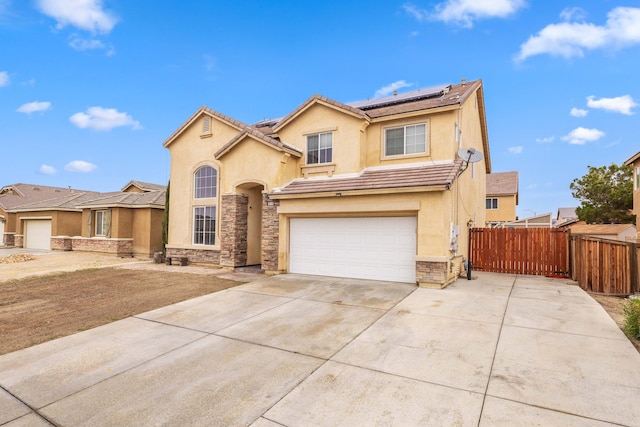 view of front of home with fence, stone siding, roof mounted solar panels, and stucco siding