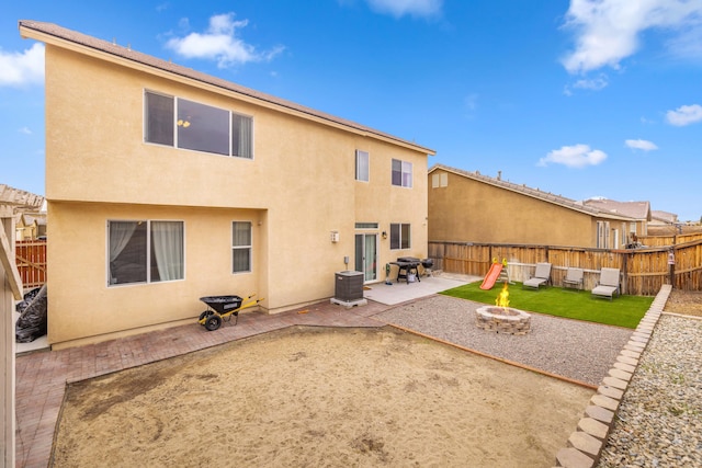 back of house with a fenced backyard, stucco siding, an outdoor fire pit, and a patio