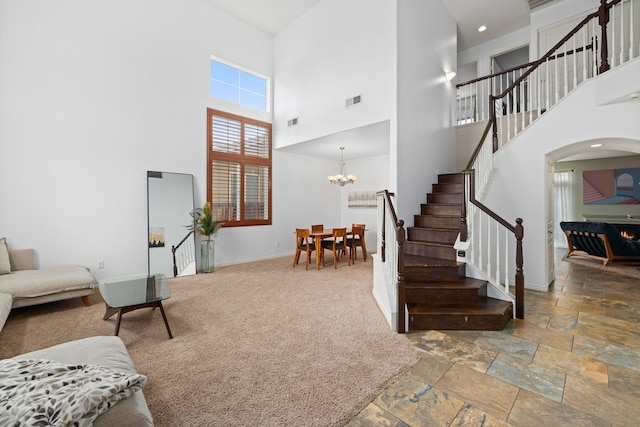 living room with stone tile floors, stairway, arched walkways, an inviting chandelier, and baseboards