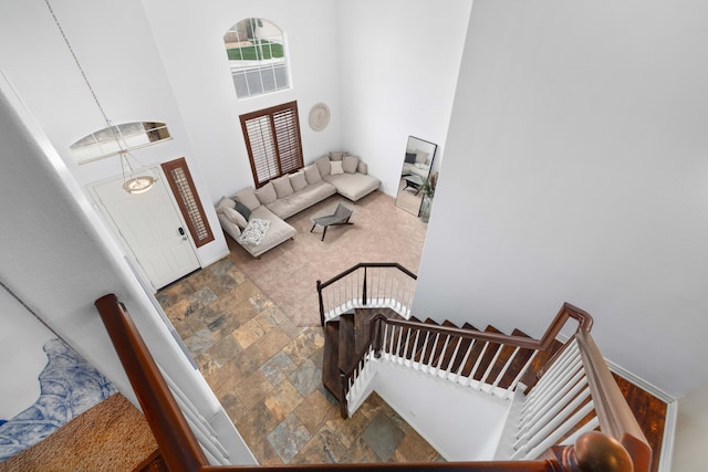 interior space with stone tile floors, carpet floors, a high ceiling, baseboards, and stairs