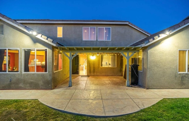 rear view of property featuring a patio and stucco siding