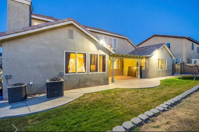 back of property featuring a trampoline, cooling unit, and stucco siding