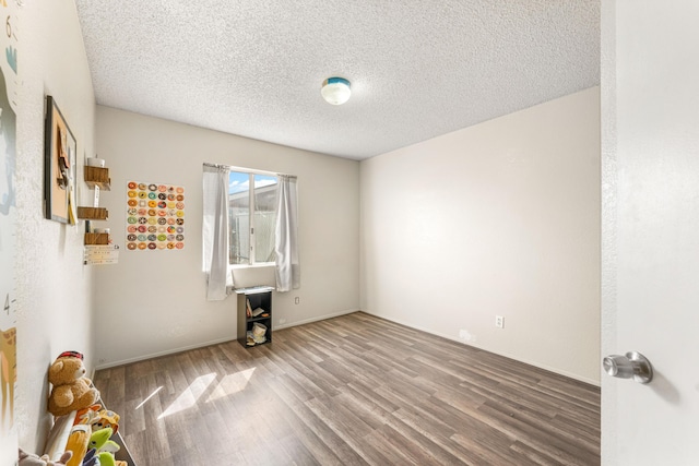 empty room with a textured ceiling and wood finished floors