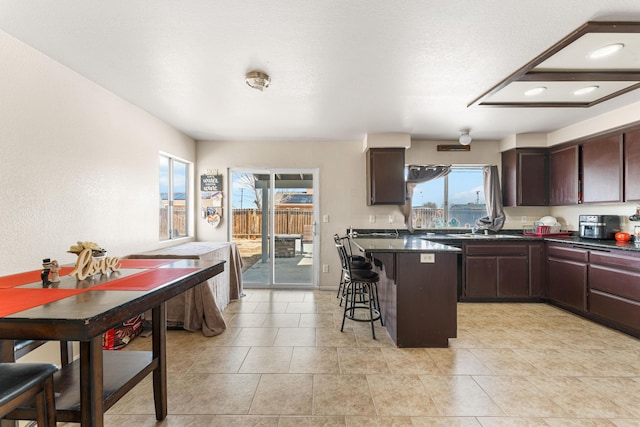 kitchen featuring a breakfast bar area, plenty of natural light, dark brown cabinets, and a kitchen island