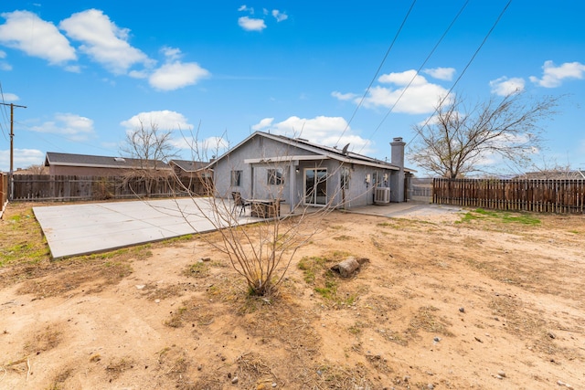 back of property with a patio, stucco siding, a fenced backyard, and a chimney