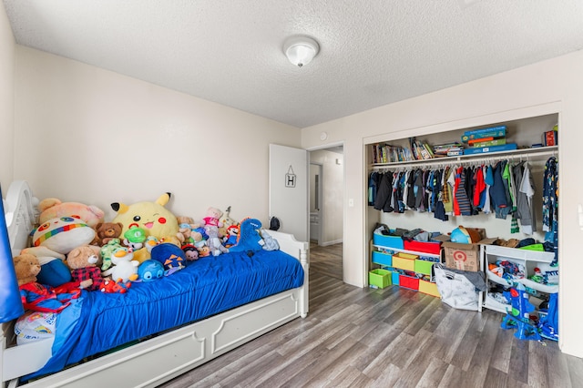 bedroom featuring a closet, a textured ceiling, and wood finished floors