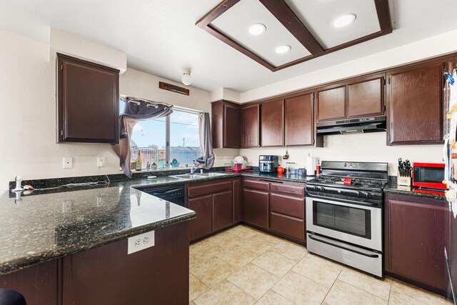 kitchen featuring stainless steel range with gas cooktop, under cabinet range hood, dishwasher, dark stone countertops, and a sink