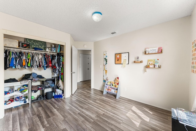 bedroom featuring a closet, a textured ceiling, visible vents, and wood finished floors