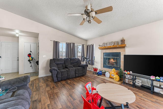 living area with a textured ceiling, wood finished floors, lofted ceiling, ceiling fan, and a tile fireplace