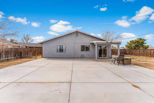 rear view of property with stucco siding, a patio, and a fenced backyard