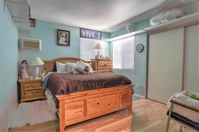 bedroom with light hardwood / wood-style floors and a wall mounted air conditioner