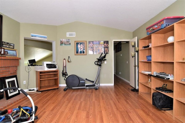 workout area with light hardwood / wood-style floors and lofted ceiling