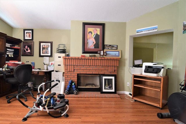 home office featuring light hardwood / wood-style flooring and a brick fireplace