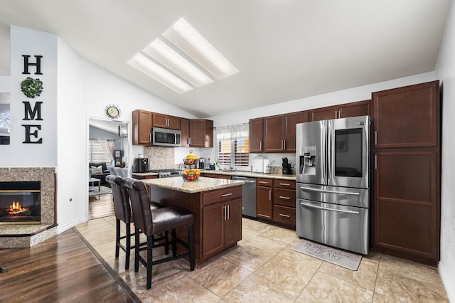 kitchen featuring tasteful backsplash, vaulted ceiling, a kitchen island, a breakfast bar, and stainless steel appliances