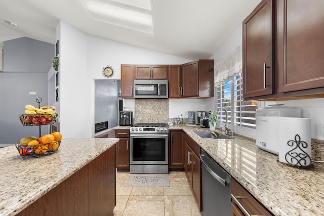 kitchen with vaulted ceiling, stainless steel appliances, light stone counters, and sink