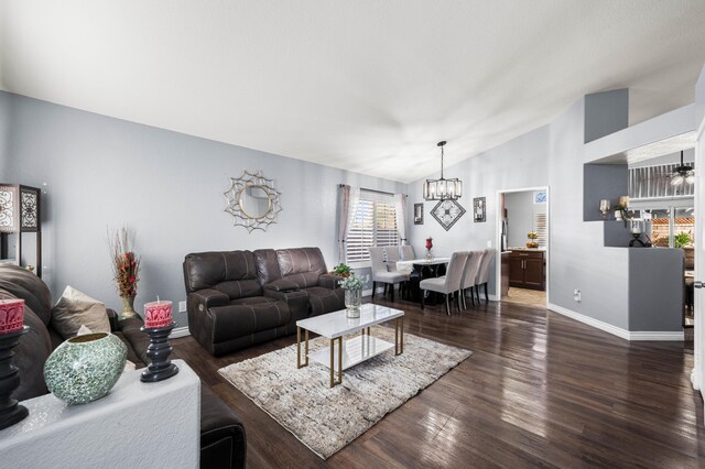 living room with lofted ceiling, dark hardwood / wood-style flooring, and an inviting chandelier