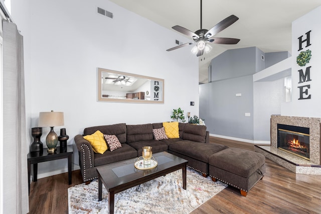 living room with high vaulted ceiling, a premium fireplace, dark hardwood / wood-style flooring, and ceiling fan