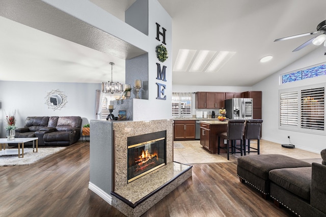 living room featuring lofted ceiling, dark hardwood / wood-style floors, and ceiling fan with notable chandelier