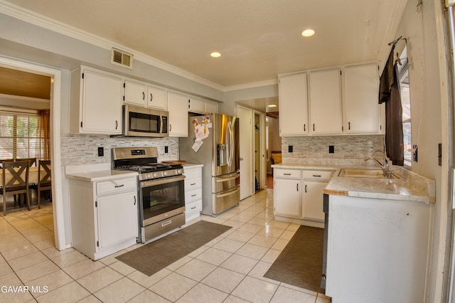 37214 Bunker Ct, Palmdale, CA 93550 - kitchen with appliances with stainless steel finishes, decorative backsplash, light tile patterned floors, crown molding, and white cabinetry