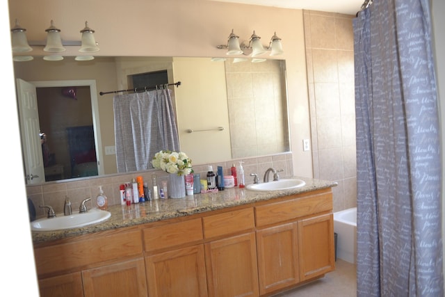 full bath featuring a sink, double vanity, backsplash, and shower / tub combo