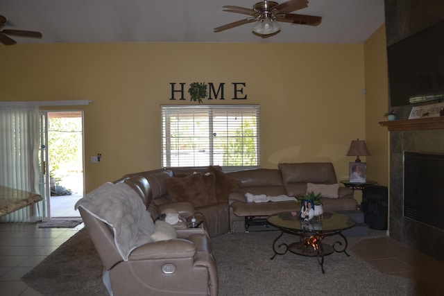 living area with a tile fireplace, a ceiling fan, and tile patterned floors