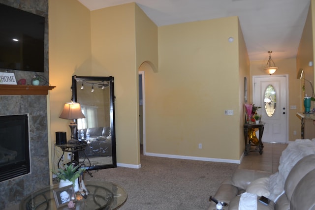 living room featuring baseboards, a tile fireplace, and carpet floors