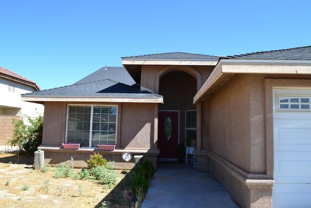 doorway to property with roof with shingles and stucco siding