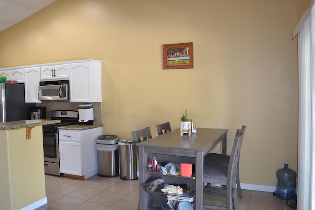 dining area with lofted ceiling and light tile patterned flooring