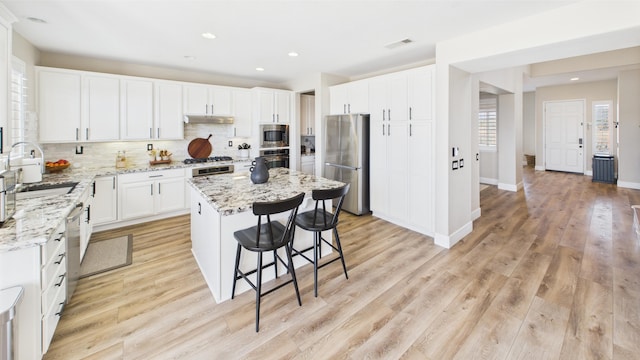 3929 Derby Cir, Quartz Hill, CA 93536 - kitchen with stainless steel appliances, a sink, under cabinet range hood, a center island, and tasteful backsplash